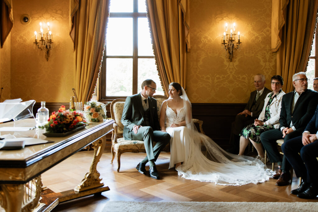 Witte trouwjurk met sleep hangend aan boom in bos Kasteel Ruurlo met zonnestralen, creatieve trouwfotografie Achterhoek