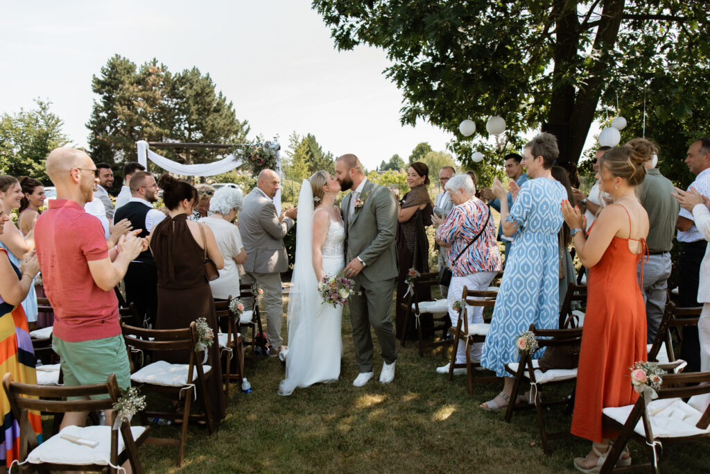 ruidspaar tijdens ceremonie in groene botanische omgeving, warm tegenlicht, zwart-wit trouwfotografie — trouwen bij Domaine d'Heerstaayen stijl